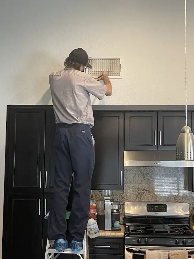 Technician inspecting an air vent during HVAC service in Volney